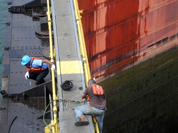 workers on the top ledge of the gate